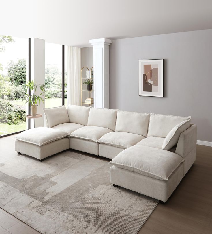 a living room with a large white sectional couch and rug on top of the floor