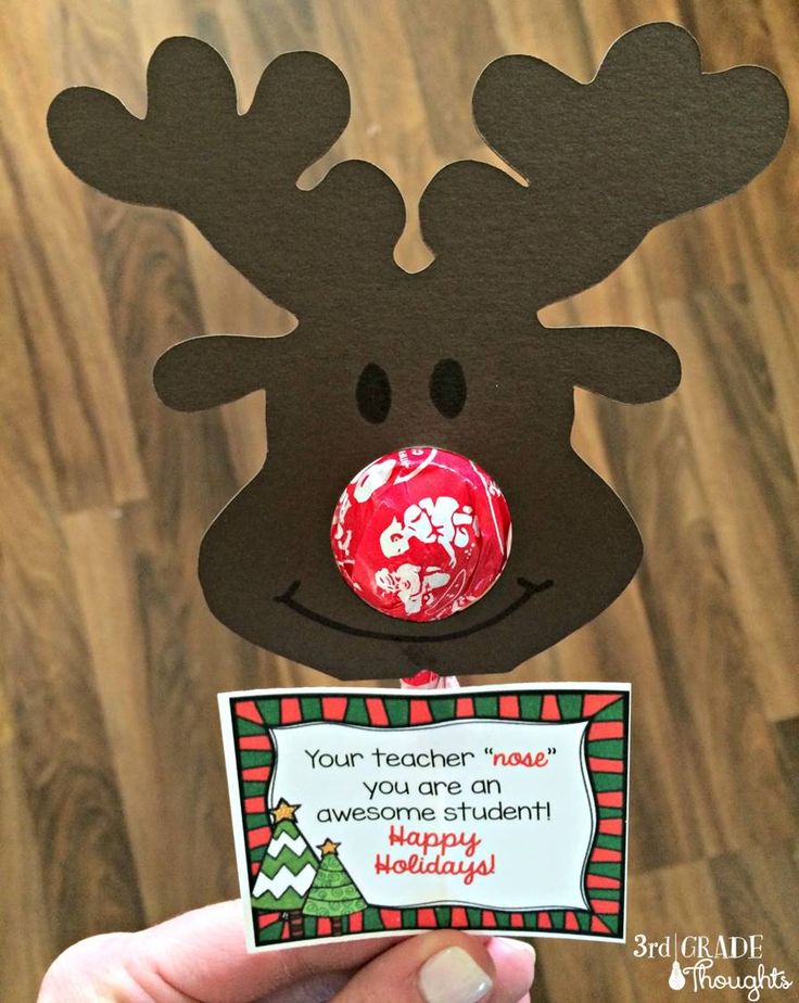 a hand holding up a card with a reindeer face on it and a candy bar in the middle