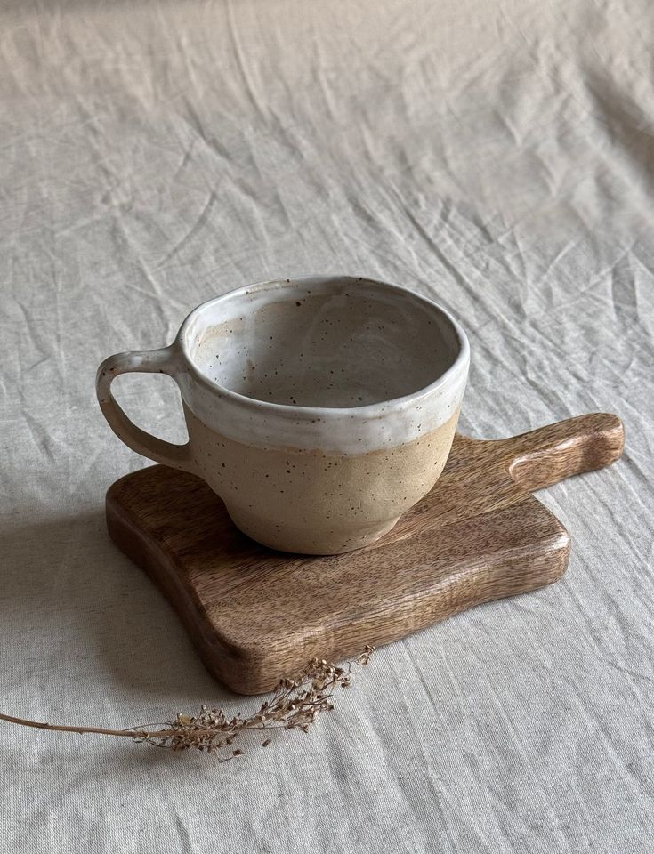 a white cup sitting on top of a wooden cutting board