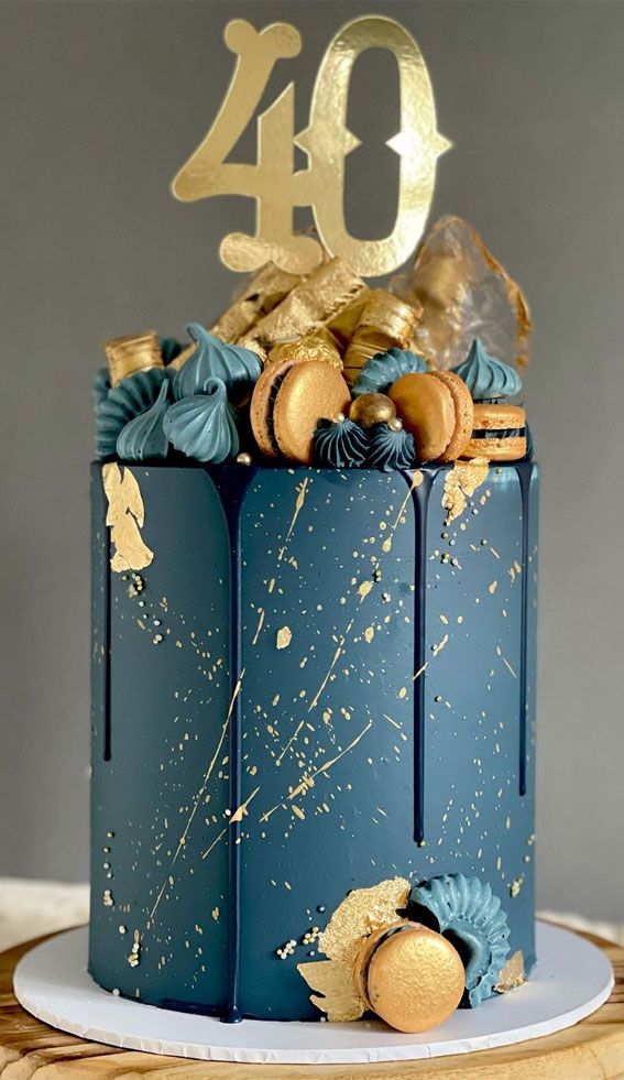 a blue cake with gold decorations on top and the number forty written in gold foil