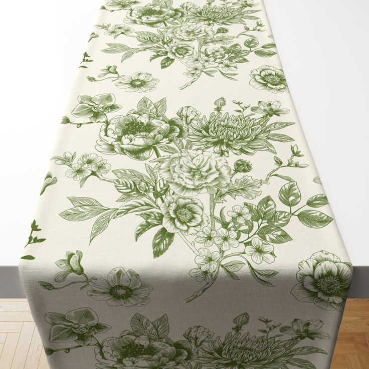 a table covered with a green and white floral print on top of a wooden floor