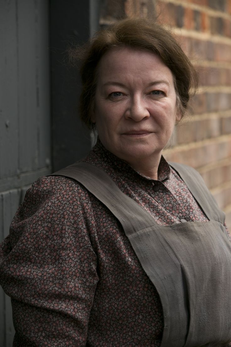 a woman standing in front of a brick wall with her hands on her hips and looking at the camera