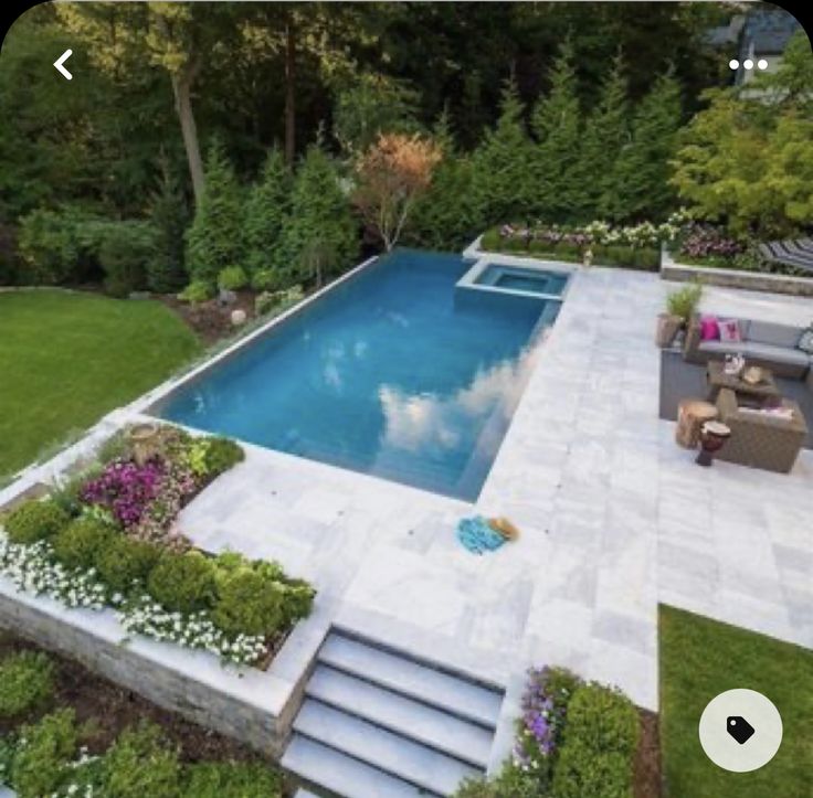 an aerial view of a pool surrounded by greenery and flowers, with stairs leading up to it