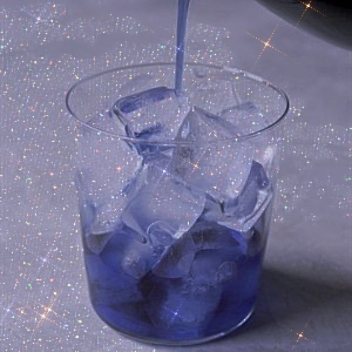 a glass filled with ice and water on top of a table