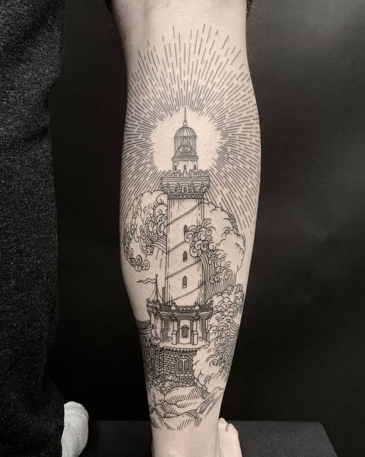 a man's leg with a lighthouse tattoo on it