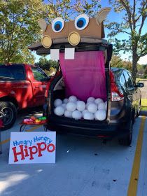 the back of a car with an open trunk filled with white balls and a sign that says happy hungry hippo