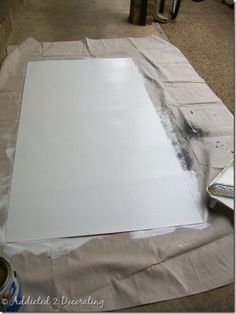 a sheet of white paper sitting on top of a piece of cardboard next to a can of paint