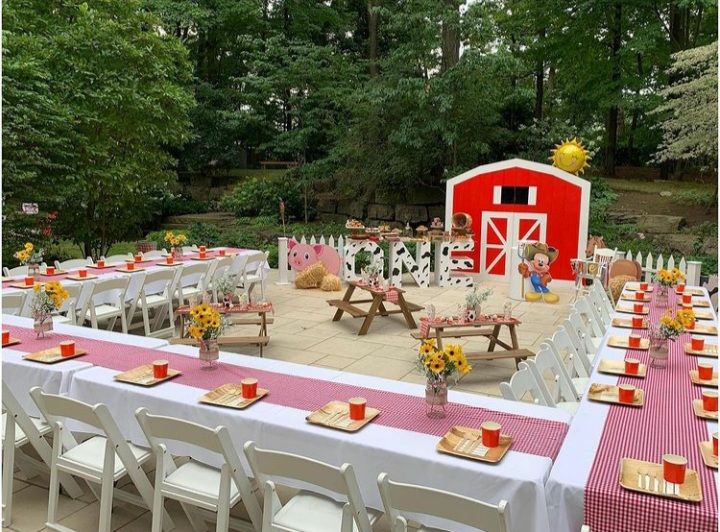 an outdoor table set up with place settings and farm animals on the tables in front of it