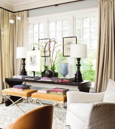 a living room filled with lots of furniture next to a window covered in white curtains