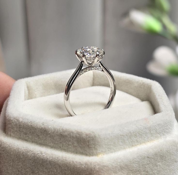 a person holding a ring in their hand with a diamond on it's side