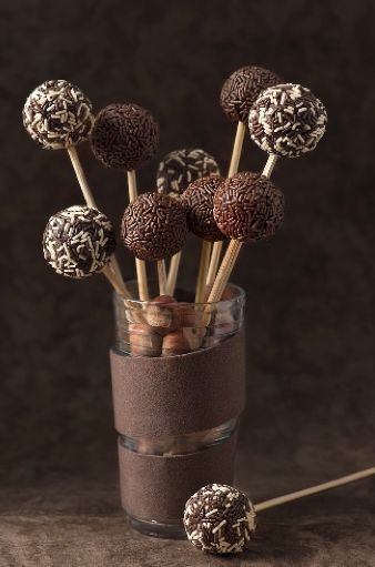 chocolate candies are arranged in a glass vase on a brown surface with two sticks sticking out of it