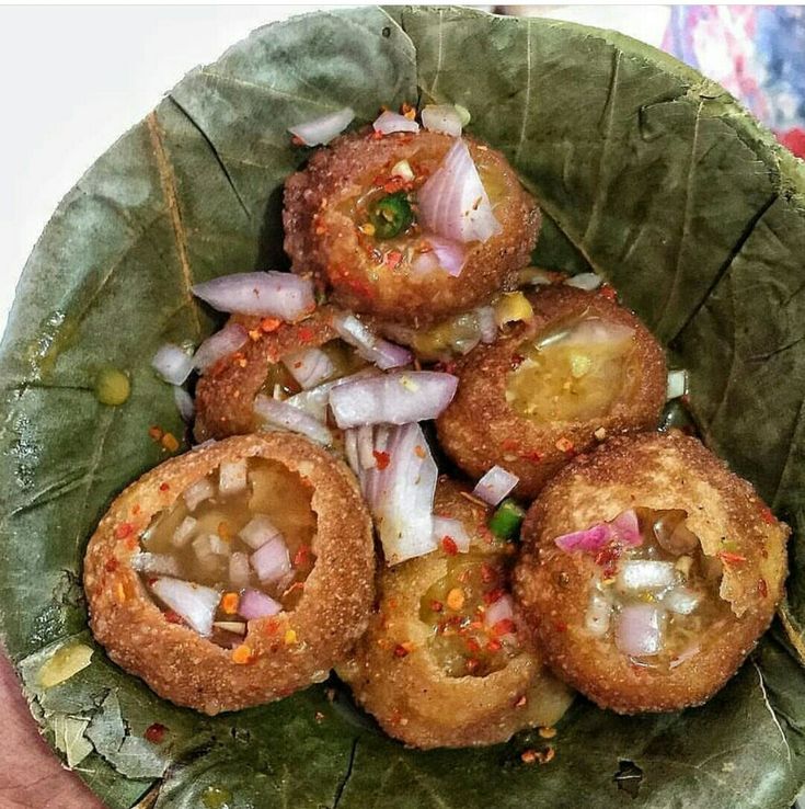 some food is in a green bowl on a table with a white plate and red napkin