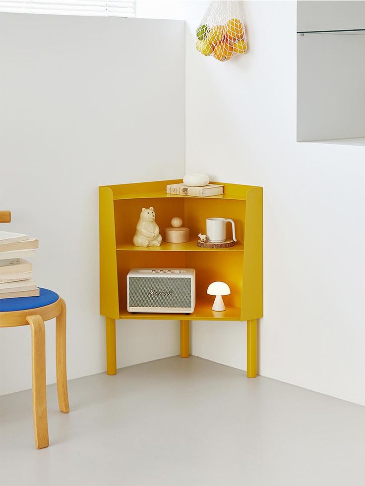 a yellow shelf with a microwave on top of it next to a small table and chair