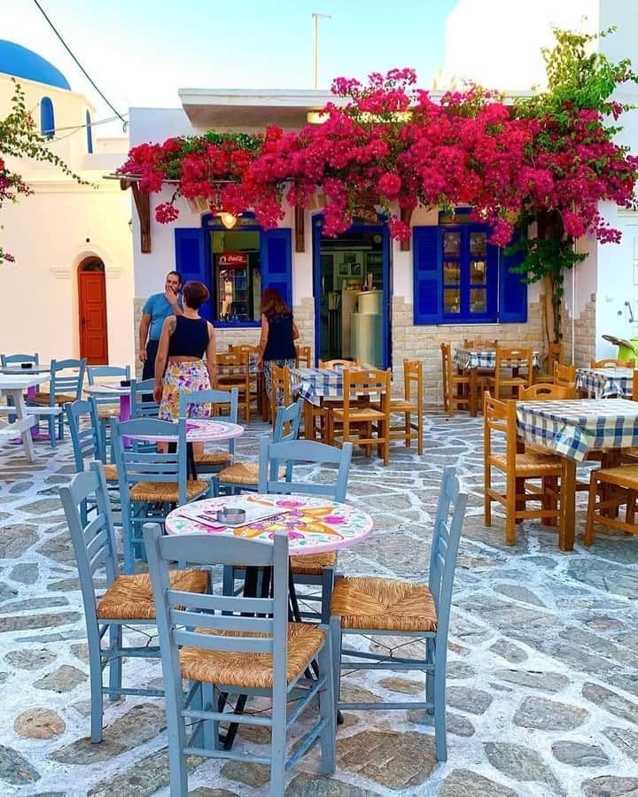 tables and chairs are set up outside in front of a building with blue shutters