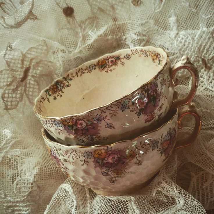 two cups sitting on top of a table covered in lace