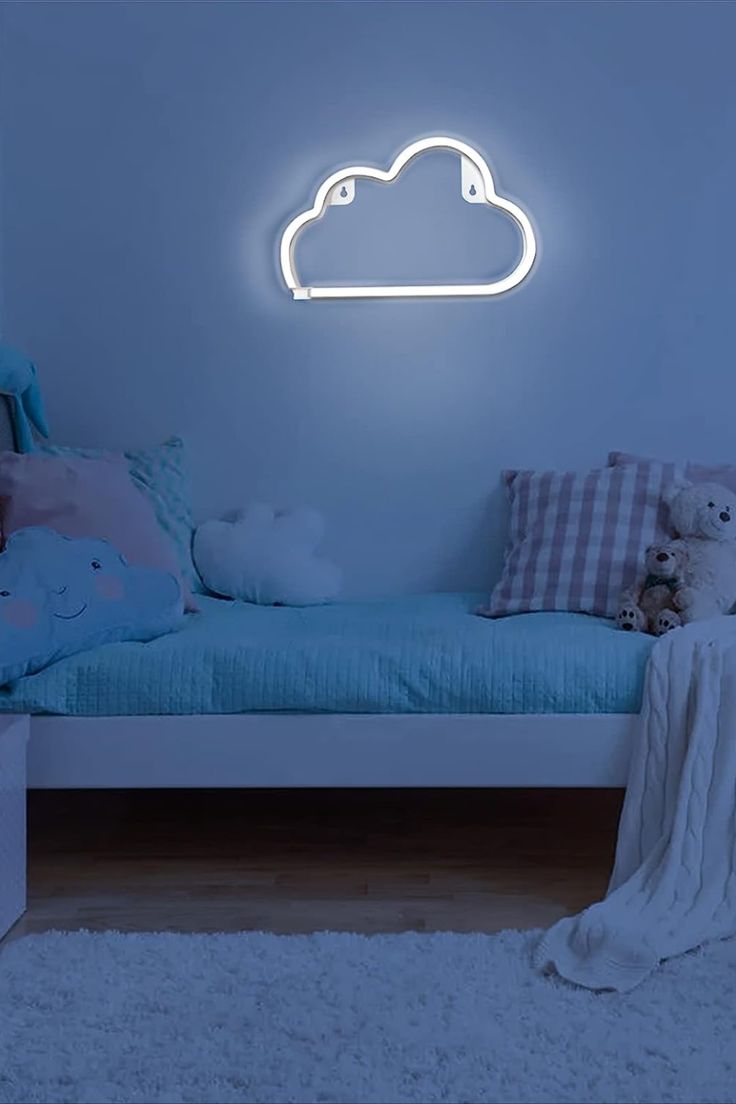 a white cloud shaped neon sign on the wall above a bed