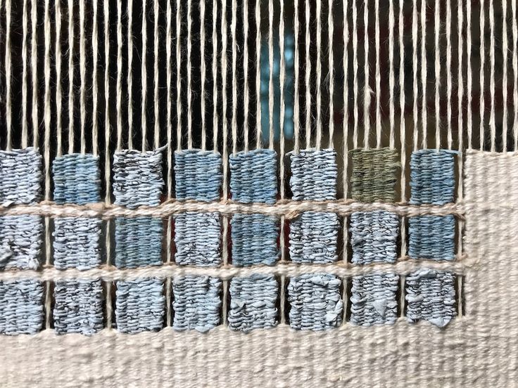 a close up of a weaving machine with blue yarn on it's sides and two rows of stitches in the middle