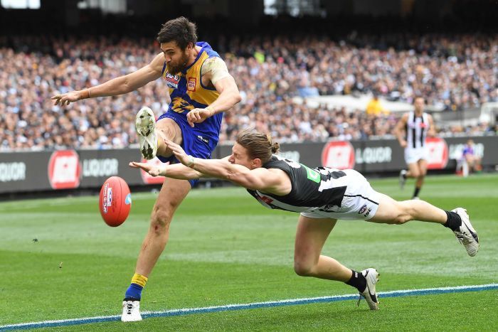 two afl players colliding for the ball in front of an audience at a sporting event