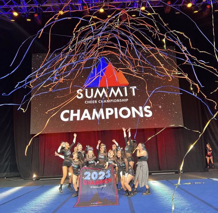 a group of women standing on top of a stage holding up their arms in the air