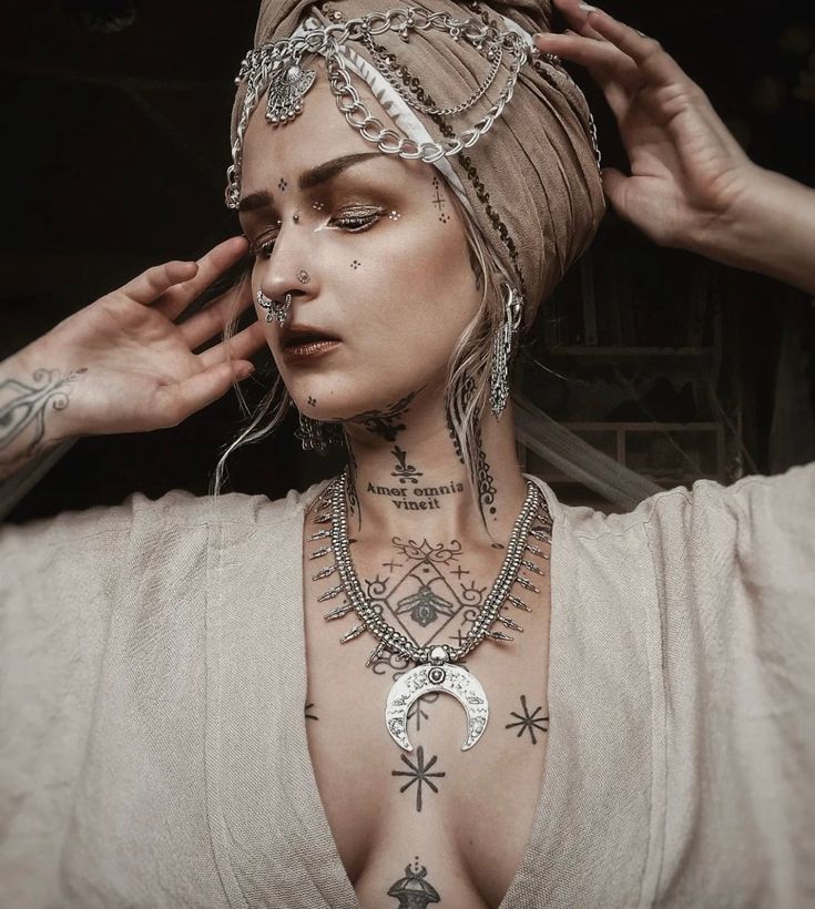 a woman with tattoos and piercings on her head is posing for the camera while wearing a scarf