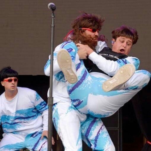 two men in blue and white outfits are performing on stage with one man holding the other