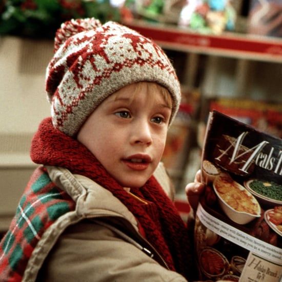 a young boy is holding a bag of chips and looking at the camera while wearing a knitted hat