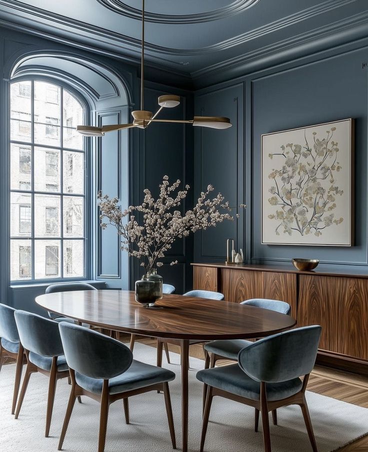 an elegant dining room with blue walls and wooden furniture, along with a large painting on the wall