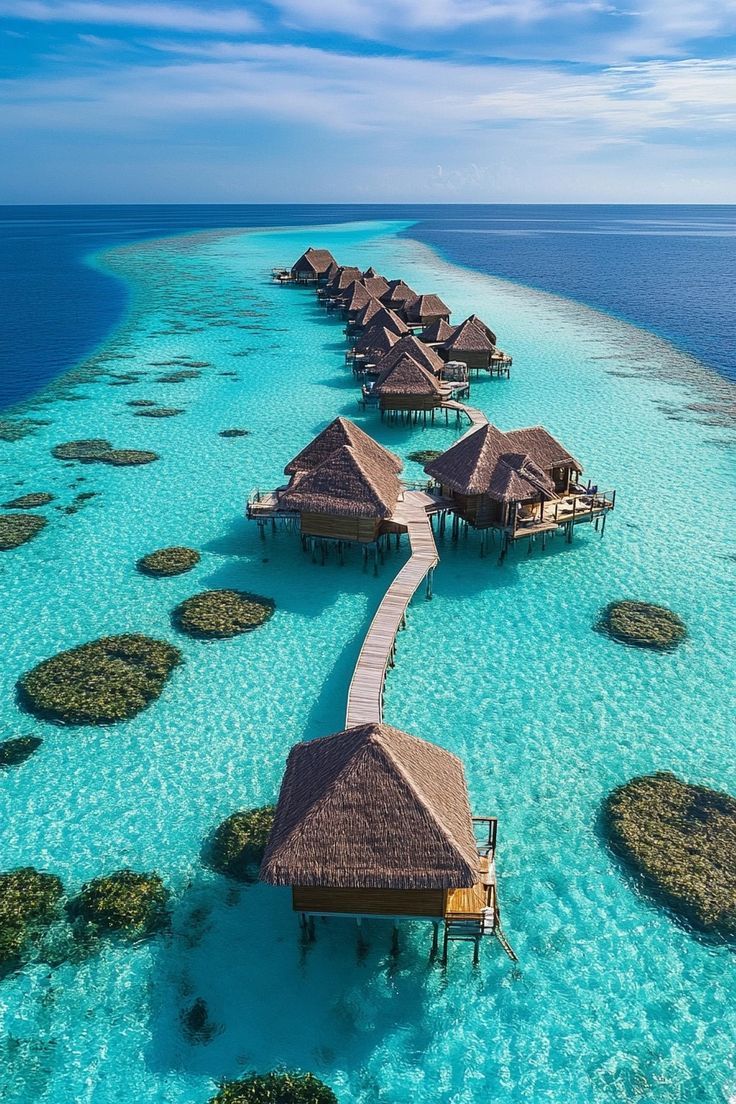 the water is crystal blue and clear with many huts on it's sides, surrounded by corals