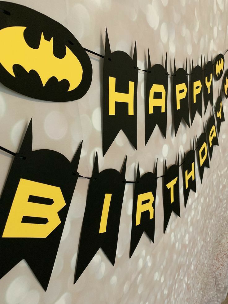 batman themed birthday banner hanging on the wall with happy birthday written in black and yellow