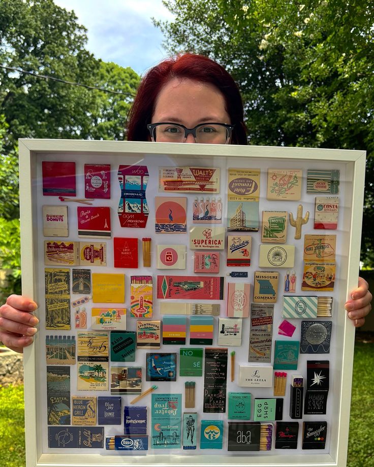 a woman holding up a large poster with many different items on it