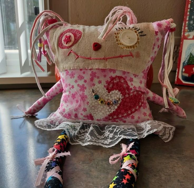 a hello kitty pillow sitting on top of a wooden table next to a pair of scissors