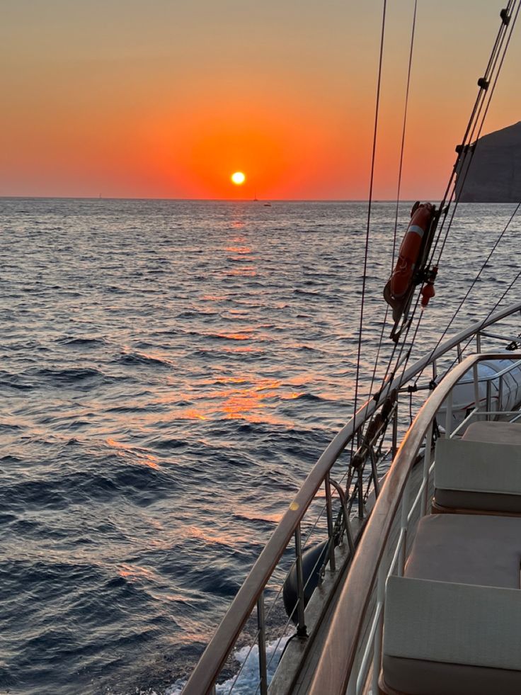 the sun is setting over the ocean on a boat