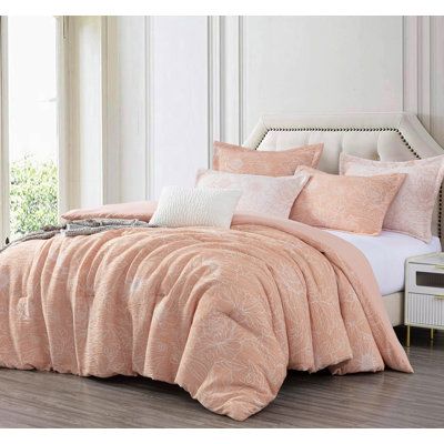 a bed with pink comforters and pillows on it