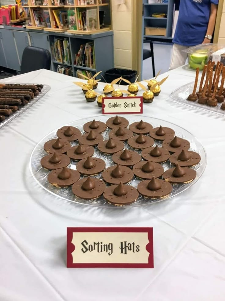 a table topped with lots of cupcakes on top of a white table cloth