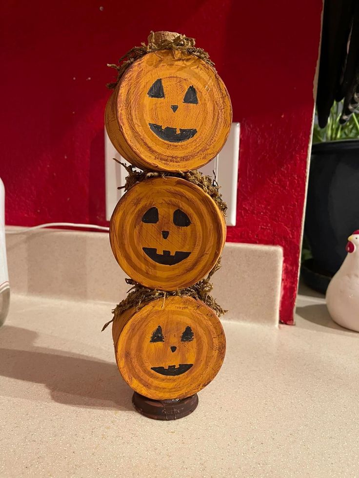 three pumpkin faces carved into wood slices