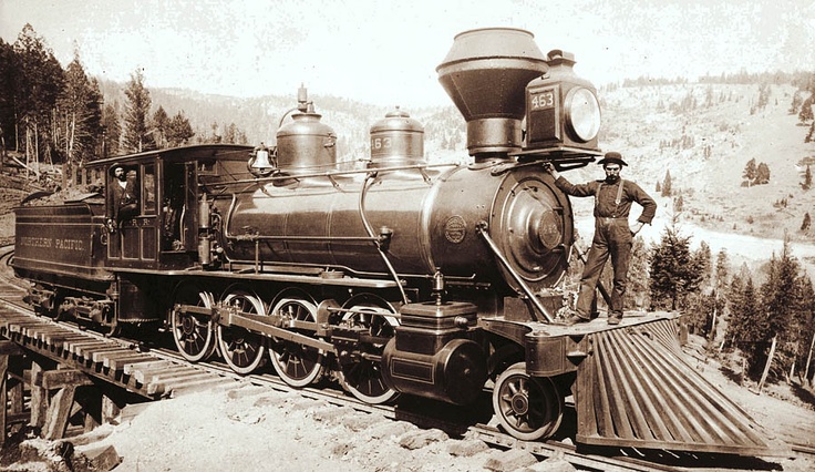 an old black and white photo of a man standing on top of a train engine