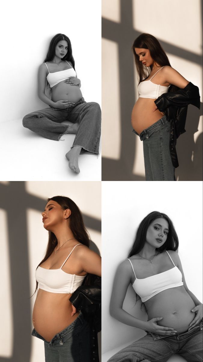 a pregnant woman sitting on the floor in jeans and white top with her belly exposed