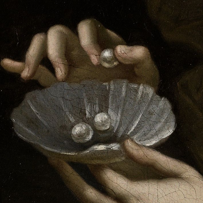 a close up of a person holding a seashell in their hands with pearls on it