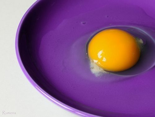 an egg is sitting in a purple bowl