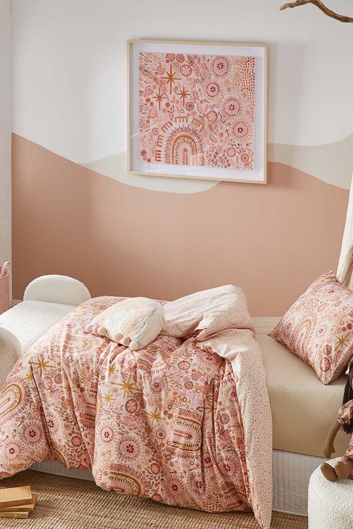 a bedroom with pink and white walls, a bed covered in blankets and pillows next to a painting on the wall