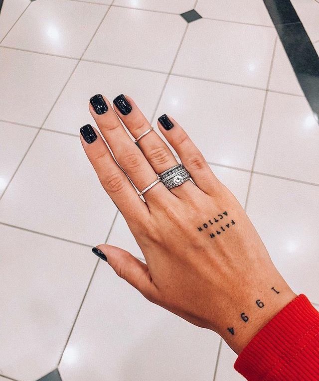 a woman's hand with black nail polish and tattoos on her left ring finger