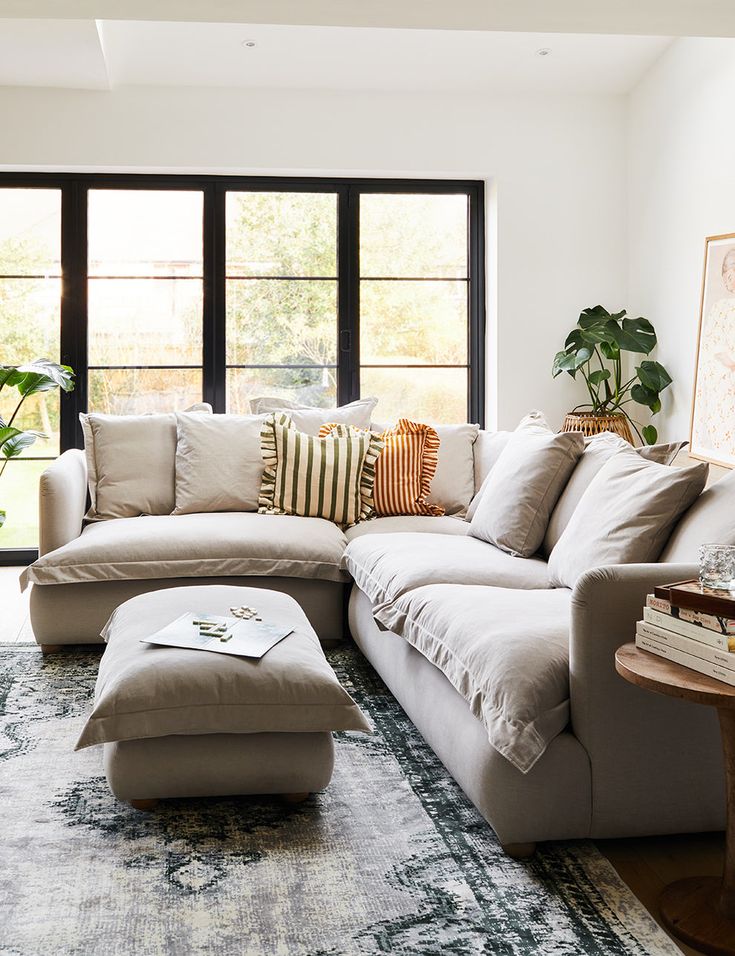 a living room with a large sectional couch and pillows on the floor next to a coffee table