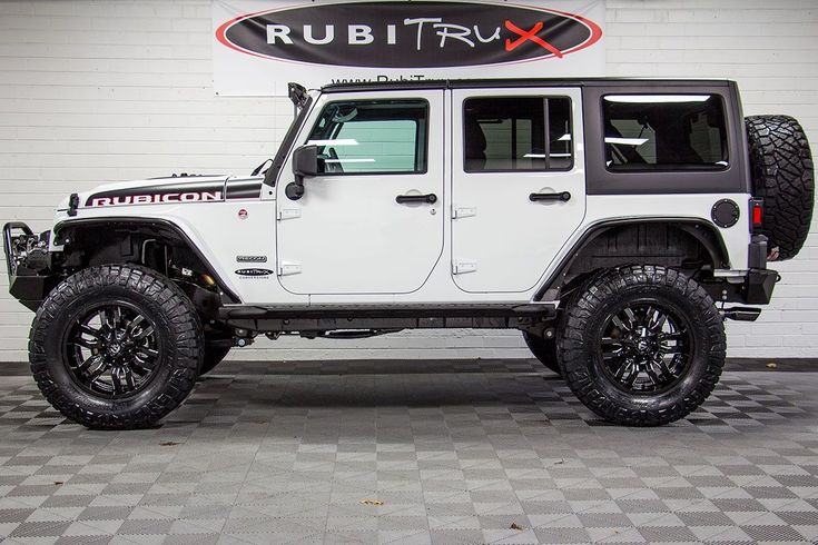 a white jeep is parked in front of a sign that says rubtrux