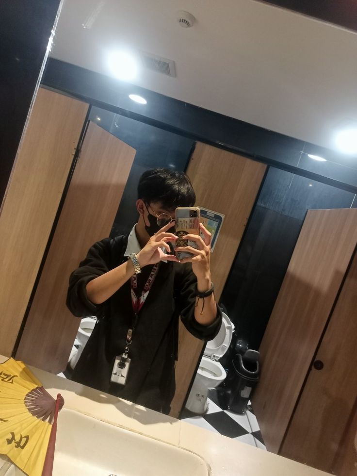 a man taking a selfie in front of a bathroom mirror with his cell phone