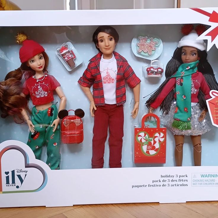 two dolls are in a box with christmas decorations on the wall behind them and one doll is wearing a santa hat