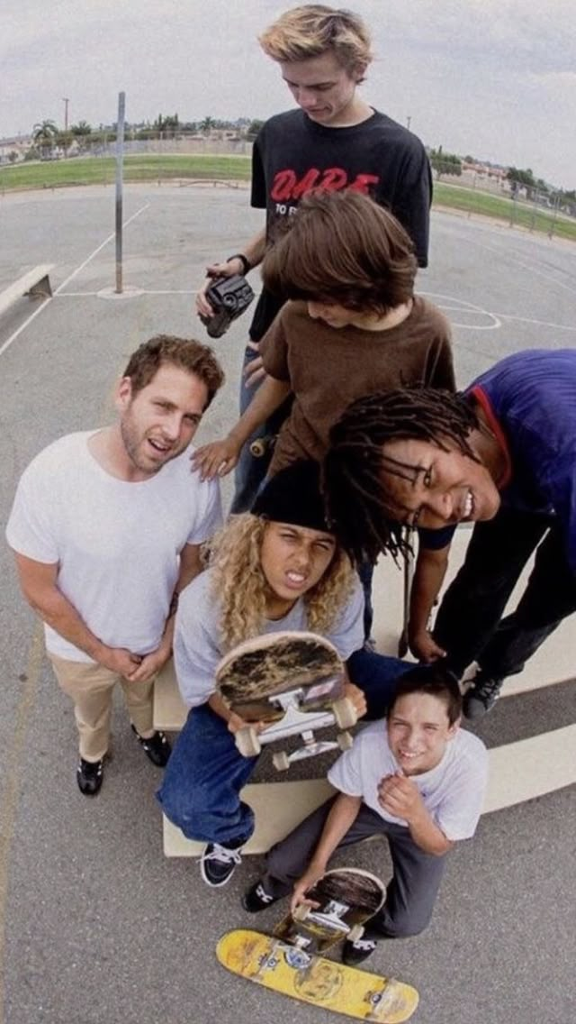 a group of young people standing around each other holding skateboards and posing for the camera