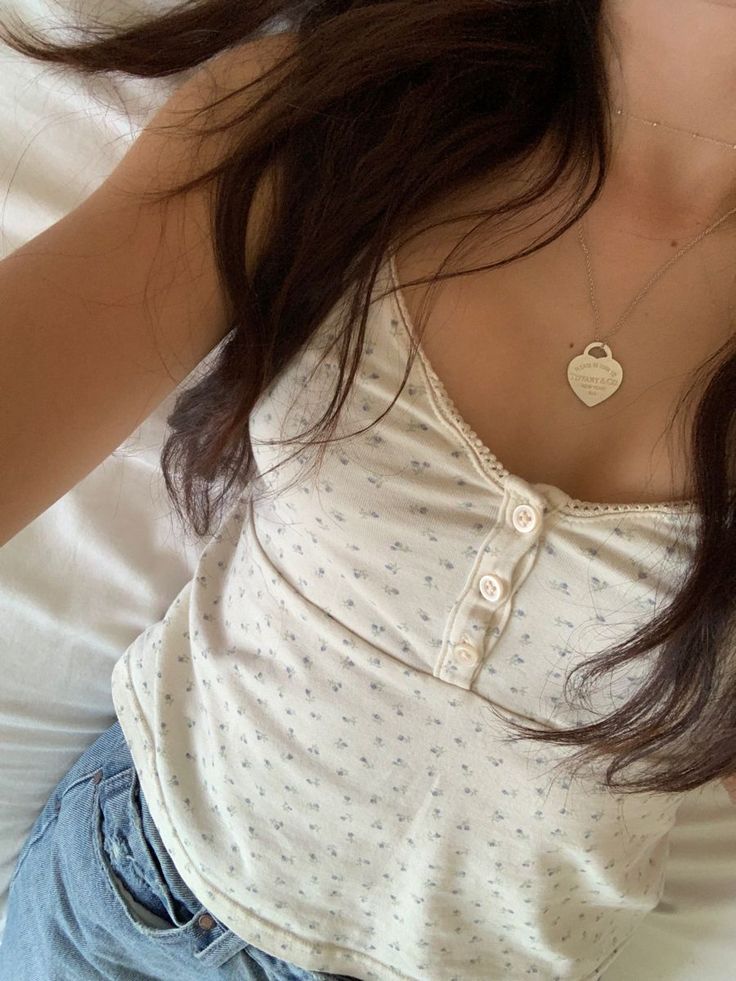 a woman laying on top of a bed wearing a white shirt