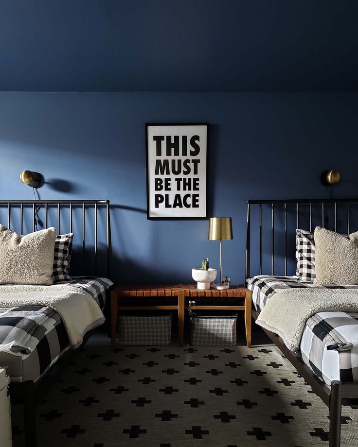 two beds in a room with blue walls and black and white checkered bedding