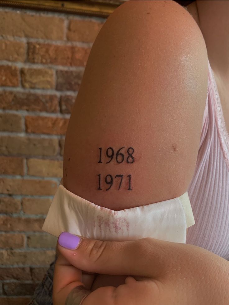 a woman with a tattoo on her arm that reads, 1908 and 1971 written in black ink