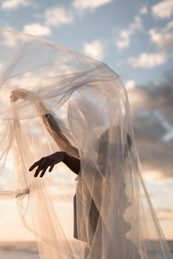 a person with a veil over their head on the beach